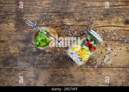 Rice salad in a glass jar with wild rice, sweetcorn, cucumber, tomato and lamb's lettuce Stock Photo