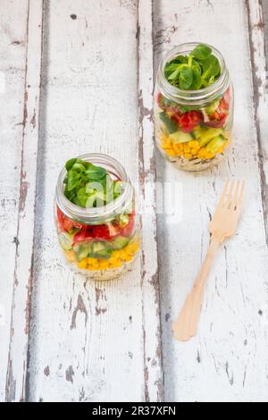 Rice salad in a glass jar with wild rice, sweetcorn, cucumber, tomato and lamb's lettuce Stock Photo
