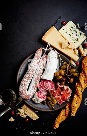 A mixed antipasti platter with olives, capers, prosciutto, dried sausage, salami, grissini, parmesan and blue cheese Stock Photo