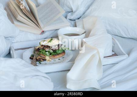 Eggs Benedict with mushrooms on a breakfast tray in a bed Stock Photo