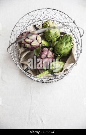 Artichokes in wire basket Stock Photo