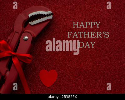Adjustable pipe wrench as a gift on red background with copy space. Construction greeting card for Fathers day. Repair home. Gifts for Dad. Buying pre Stock Photo