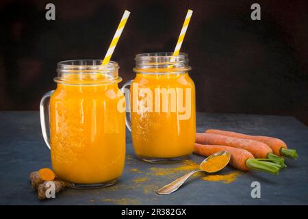 Carrot and turmeric smoothie in two glasses with straws Stock Photo