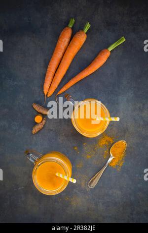 Carrot and turmeric smoothie in glasses with straws (seen from above) Stock Photo