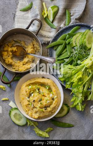 Yellow pea dip with cucumber, sugar snap peas, celery and pea leaves Stock Photo