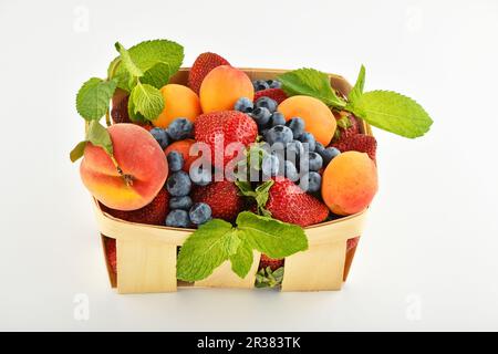 Strawberries, apricots, blueberries, peach in basket isolated on white Stock Photo