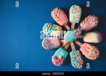 Different cake pops in the shape of ice lollies with brightly coloured icing Stock Photo