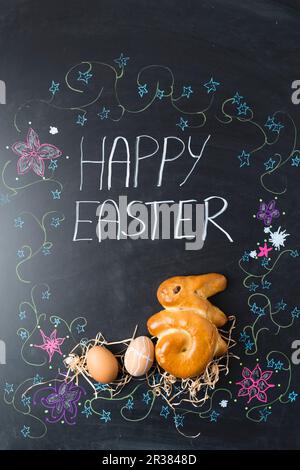 Easter eggs and a bunny (shaped yeast bread) on a chalkboard Stock Photo