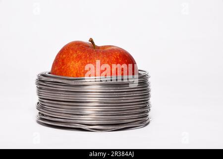Wired apple: whole red apple in coils of aluminum wire isolated on white background Stock Photo