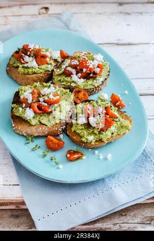 Bruschetta with courgette pesto, roasted tomatoes, feta cheese and thyme Stock Photo
