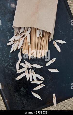 Various types of wholemeal pasta in a paper bag Stock Photo