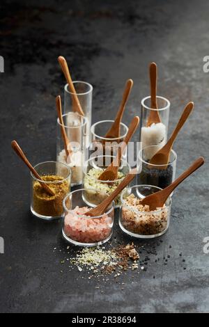 A still life of different salt varieties in glass jars with wooden spoons Stock Photo