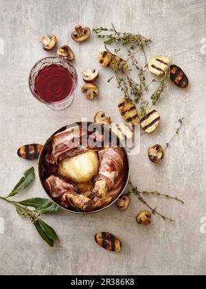 Coq au Vin with grilled potato halves, mushrooms, thyme, and a glass of red wine Stock Photo