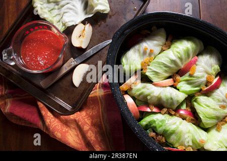 Stuffed cabbage in roasting pan with apple slices, rasins and tomato sauce Stock Photo