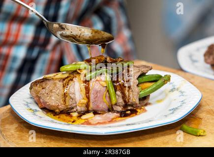 Drizzling meat juices over beef roulade Stock Photo