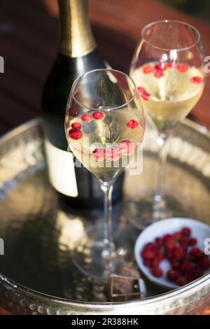 A bottle and two glasses of champagne with wild strawberries on a silver tray Stock Photo