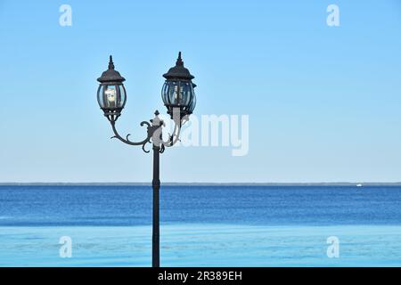 Old vintage street lamppost over blue seascape Stock Photo