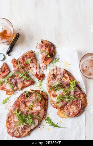 Quick pita bread pizza with sliced tomatoes, prosciutto, mozzarella and fresh rocket Stock Photo