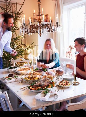 A family sitting around a table set for Christmas dinner Stock Photo