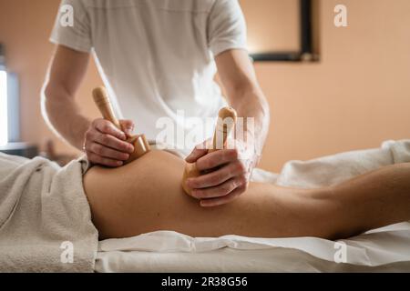 Unknown Caucasian woman having madero therapy massage anti-cellulite  treatment by professional therapist holding wooden tools in hands in studio  or sa Stock Photo - Alamy