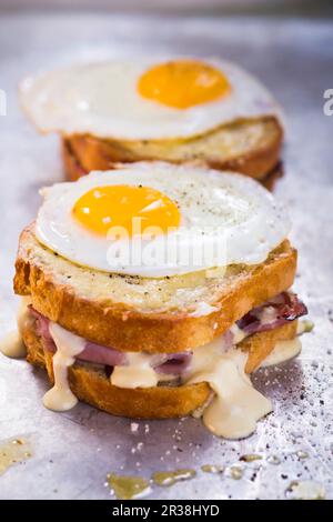 Croque Madame; Ham and Gruyere Cheese Grilled Sandwich with Herbed Aioli and Bechamel Sauce Topped with a Sunny Side Up Fried Egg Stock Photo