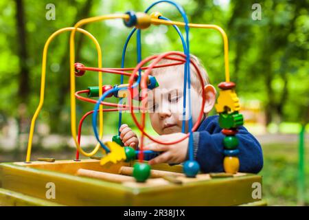 Little kid boy plays with a multicolored logical toy Stock Photo