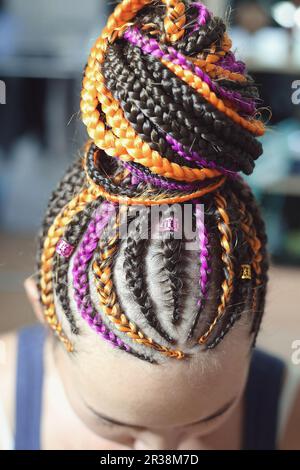 Pigtails orange and brown with artificial hair braided and collected in a high tail, close-up hairstyles on the head of a girl Stock Photo