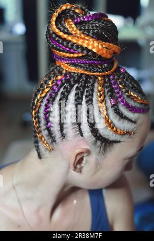 Pigtails orange and brown with artificial hair braided and collected in a high tail, close-up hairstyles on the head of a girl Stock Photo