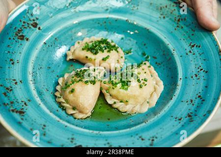 Kärntner Kasnudeln (Austrian ravioli filled with quark and potatoes) with chives on a plate Stock Photo