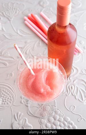 A slushy Frosé in a cocktail glass with a bottle of rosé wine Stock Photo