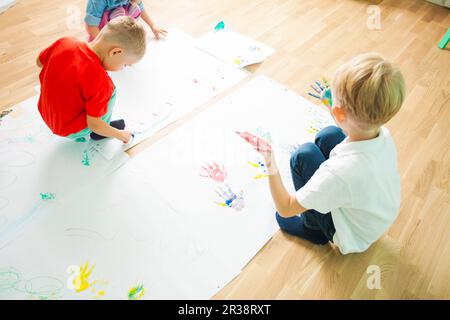 Top view of two kids drawing on a floor Stock Photo