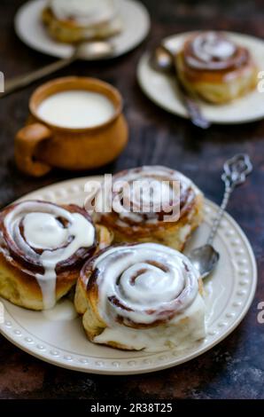 Yeast buns cinnamon on a plate and a mug of milk Stock Photo