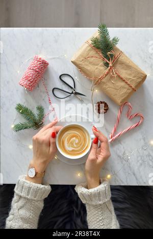 A woman holding a cup of coffee in her hands, a marble table and coffee Stock Photo