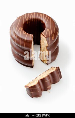A sliced Baumkuchen (German layer cake) with chocolate glaze on a white surface Stock Photo