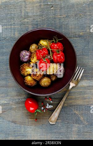 Oven-baked potatoes, Brussels sprouts and cherry tomatoes in a bowl Stock Photo