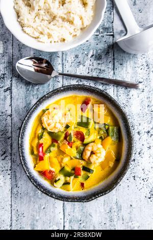 Thai curry made with pepper, mange tout, courgette, coconut milk and prawns served with rice Stock Photo