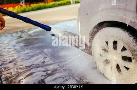 Foaming the car with the foam. Car wash. Man washing car on the self washing service. High pressure water. Pressure washer. Cleaning the car. Stock Photo