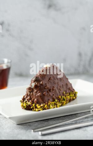 Dessert Cake from Malaga on stone table. Cake with banana inside, covered with chocolate sauce and hazelnuts Stock Photo