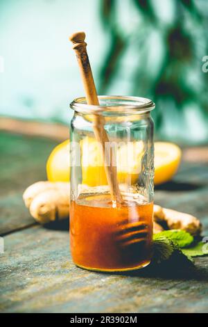 Ingredients for making immunity boosting natural drink: Lemons, mint, ginger, honey on wooden table over blue wall background Stock Photo