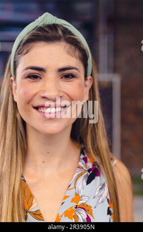 Portrait of happy biracial businesswoman looking at camera in office, unaltered Stock Photo