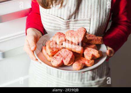 Child's hands holding pink heart cookies for Valentines day Stock Photo