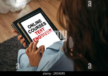 Online learning concept. A woman holds a tablet in her hands on the screen of which it is written - online courses Test Engineer Stock Photo