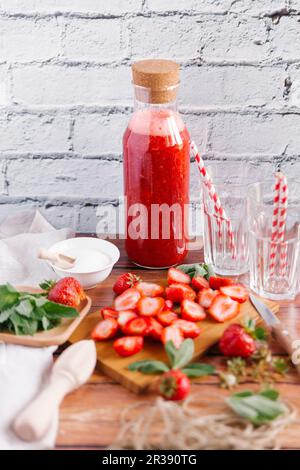 Strawberry smoothie in a bottle and sliced strawberries on a wooden board Stock Photo
