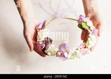 Woman's hands hold foam wreath with sprint flowers Stock Photo