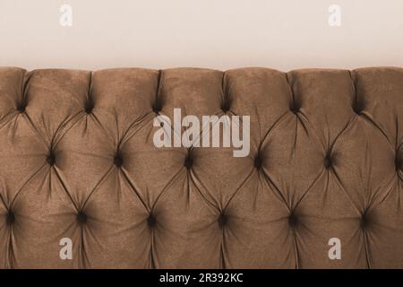 Brown velvet capitone textile capitone bed headboard of Chesterfiels style sofa, close-up Stock Photo