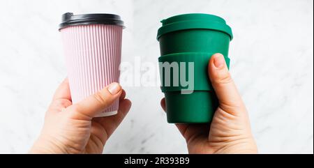 Hands hold paper coffee cup and bamboo reusable drink mug Stock Photo