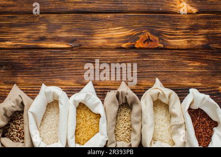 Different rice types in textile bags on wooden background Stock Photo