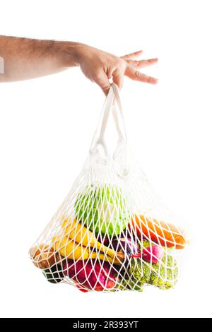 Male hand holds cotton mesh bag with fresh food Stock Photo