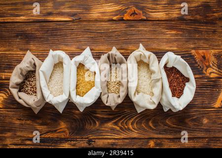 Different rice types in textile bags on wooden background Stock Photo