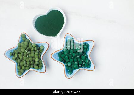 Spirulina algae powder and tablets on white marble Stock Photo